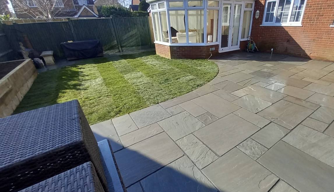 New sandstone patio with curved lawn edge beside a conservatory, Kent